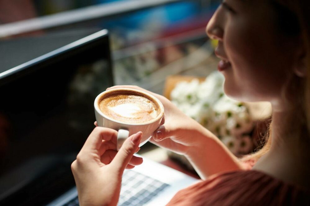 kobieta pijąca kawę przy laptopie