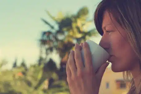 woman enjoying a drink outdoors on a sunny day 2026 04 13 00 39 01 utc Dlaczego kawa jest gorzka? 8 błędów podczas mielenia i parzenia